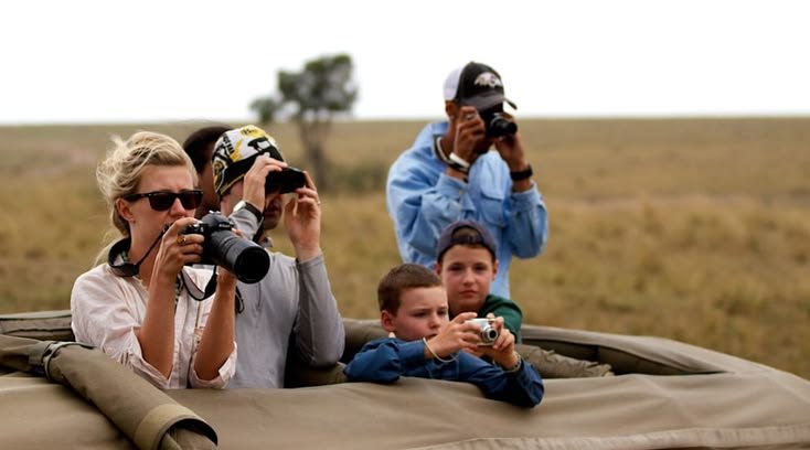 Family on a safari vehicle photographing wildlife together with children